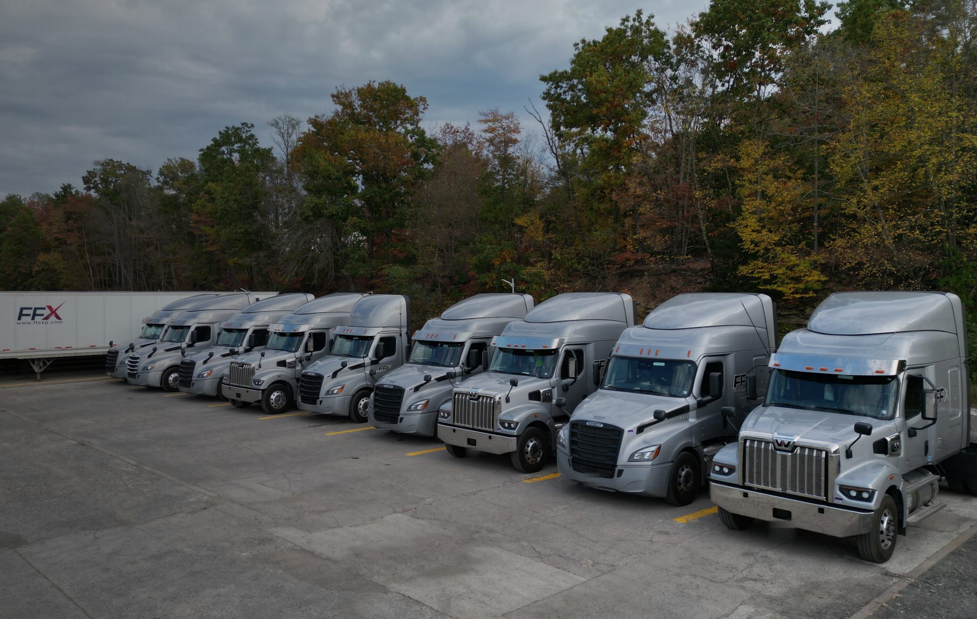 Silver FFX Freightliner Cascadia and Western Star trucks lined up at the FastFreight Express terminal in Windber, PA